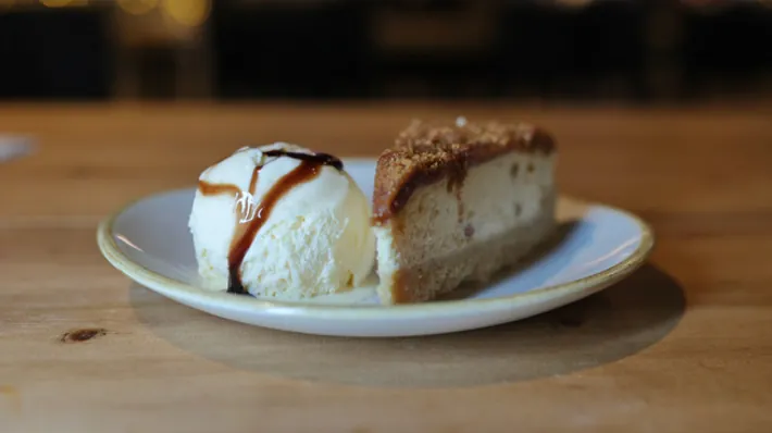 A slice of cheesecake with a scoop of ice cream