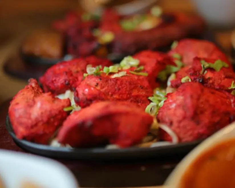 Tandoori chicken pieces on a sizzling plate