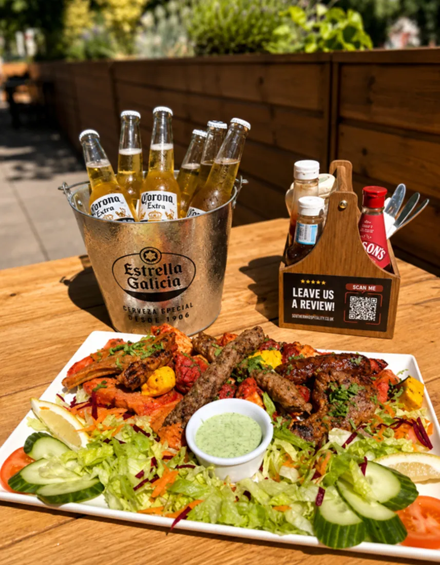 A mixed grill platter with salad and mint chutney, next to a bucket of beers