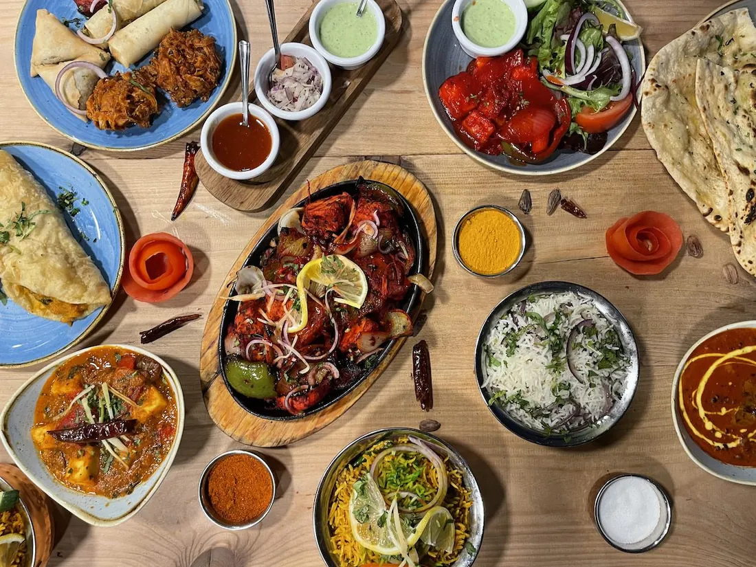 A table of Indian dishes with naan, rice, samosas and chutneys