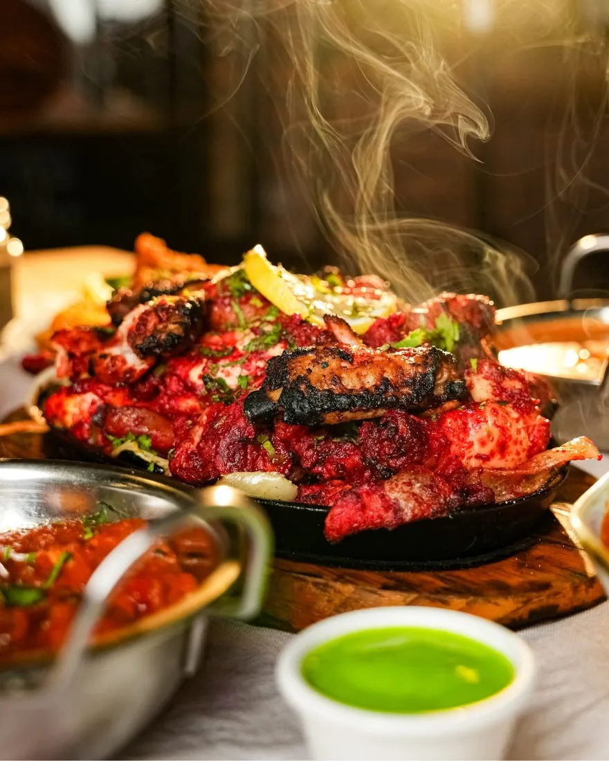 Tandoori chicken sizzling on a cast-iron platter