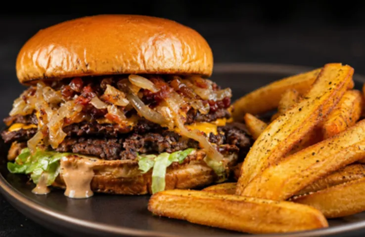 A double smash burger with caramelised onions and potato wedges